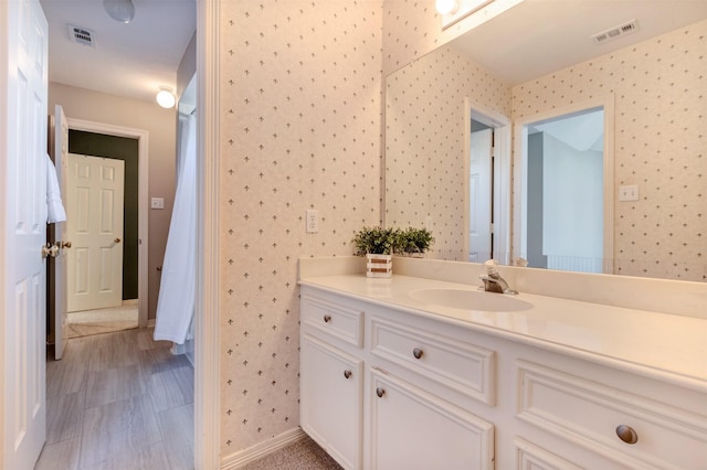 bathroom featuring wallpapered walls, visible vents, and vanity