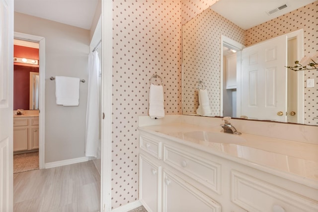 bathroom featuring vanity, baseboards, visible vents, a shower with curtain, and wallpapered walls