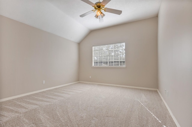 carpeted spare room featuring lofted ceiling, ceiling fan, and baseboards