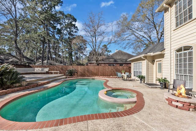 view of pool with a pool with connected hot tub, a patio area, a fenced backyard, and a fire pit