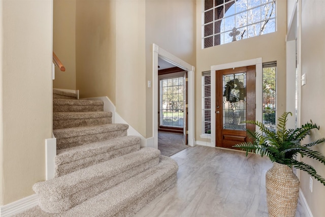 entrance foyer featuring baseboards, stairway, and a towering ceiling