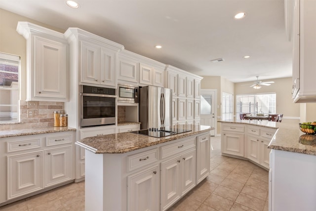 kitchen featuring ceiling fan, stainless steel appliances, tasteful backsplash, and white cabinets