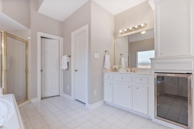 bathroom featuring tile patterned flooring, a washtub, vanity, baseboards, and a shower stall