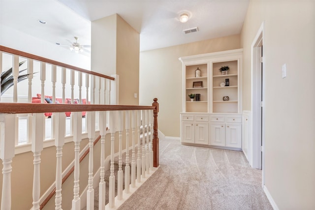 corridor featuring an upstairs landing, baseboards, visible vents, and light colored carpet