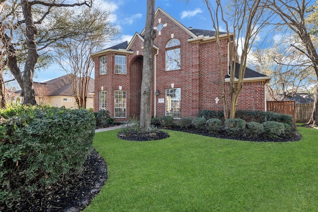 traditional-style home with a front yard, fence, and brick siding