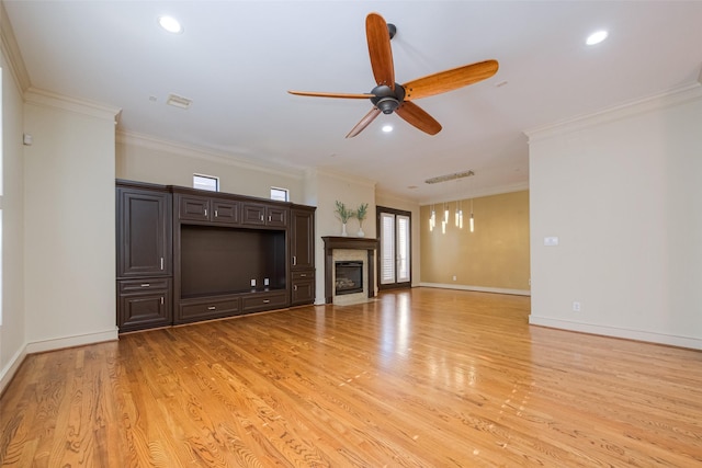 unfurnished living room with baseboards, a glass covered fireplace, crown molding, and light wood finished floors