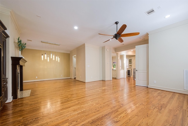 unfurnished living room featuring light wood-style flooring, a fireplace with flush hearth, visible vents, and ornamental molding