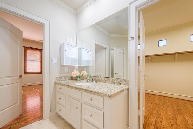 bathroom with wood finished floors, vanity, baseboards, and ornamental molding