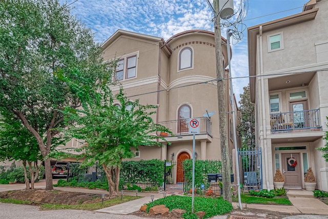 view of front facade with a fenced front yard, stucco siding, and a balcony