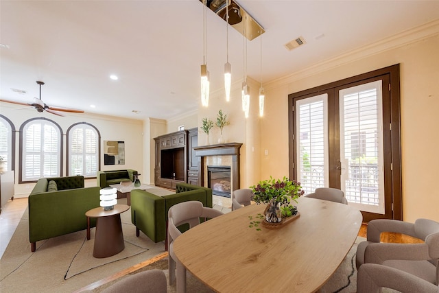 dining space with a tiled fireplace, french doors, visible vents, and ornamental molding