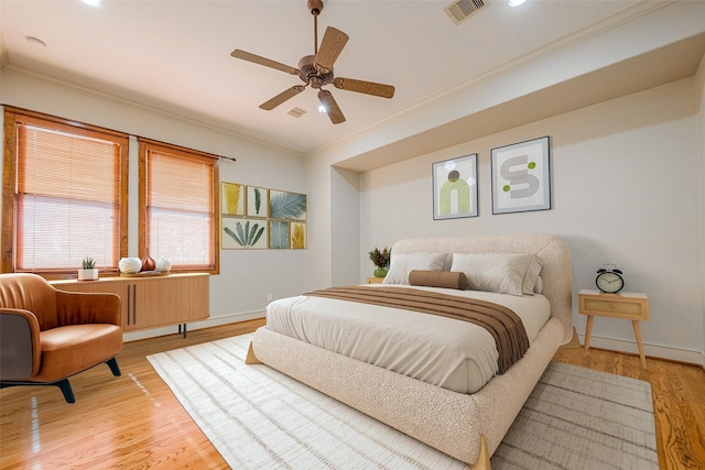 bedroom featuring visible vents, crown molding, ceiling fan, baseboards, and light wood-type flooring