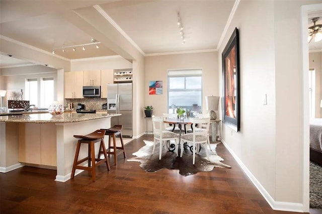 dining space with dark wood-style floors and ornamental molding