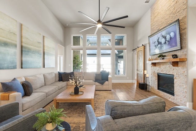 living area with a barn door, a fireplace, a high ceiling, and wood finished floors