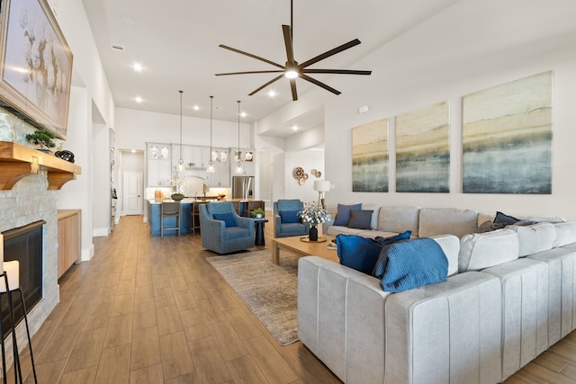 living room featuring recessed lighting, a fireplace, a ceiling fan, and light wood-style floors