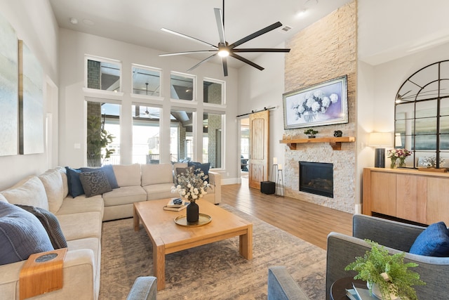 living room with a ceiling fan, wood finished floors, a towering ceiling, and a barn door