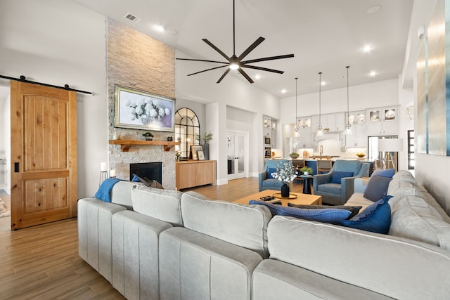 living area with wood finished floors, a barn door, a towering ceiling, and visible vents