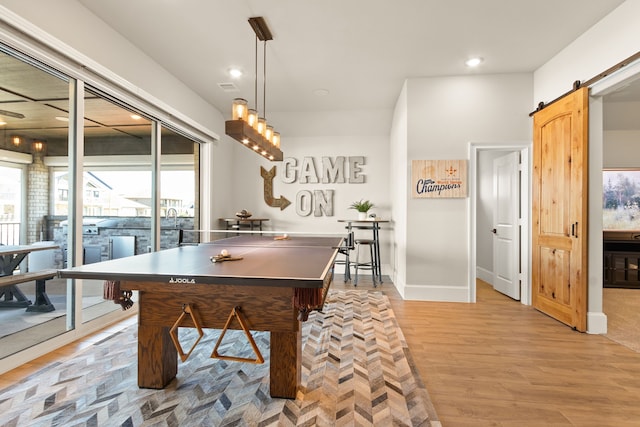 rec room with a barn door, visible vents, baseboards, light wood-style floors, and recessed lighting