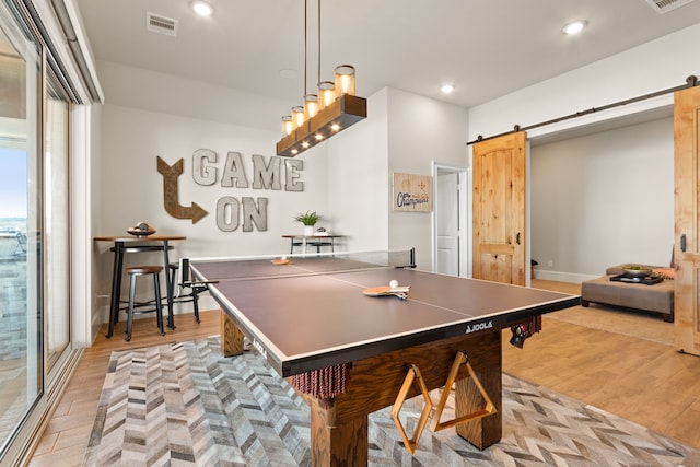 playroom featuring recessed lighting, visible vents, a barn door, light wood-type flooring, and baseboards