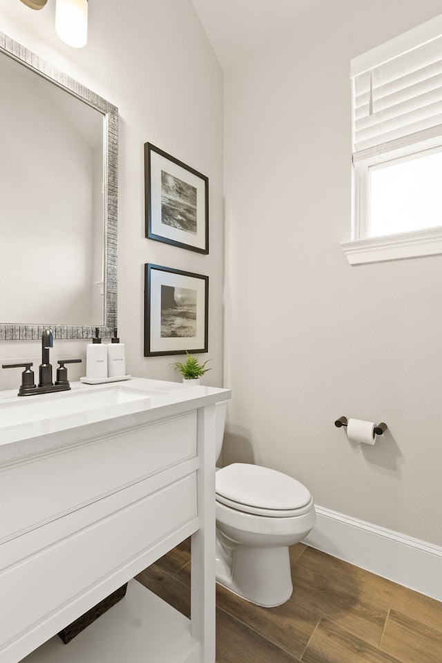 bathroom featuring baseboards, vanity, toilet, and wood finished floors