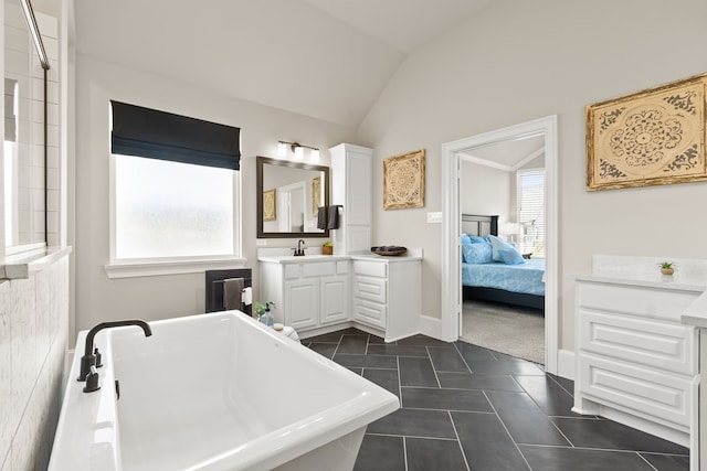 full bathroom featuring a healthy amount of sunlight, vaulted ceiling, a freestanding bath, and tile patterned floors