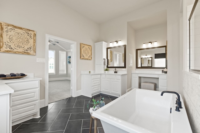 full bathroom featuring vanity, baseboards, a freestanding bath, and tile patterned floors