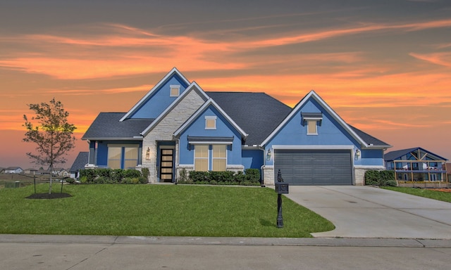 craftsman-style house featuring a garage, a shingled roof, driveway, stone siding, and a front yard