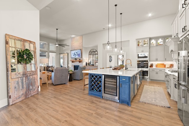 kitchen featuring ceiling fan, beverage cooler, a sink, light countertops, and blue cabinetry