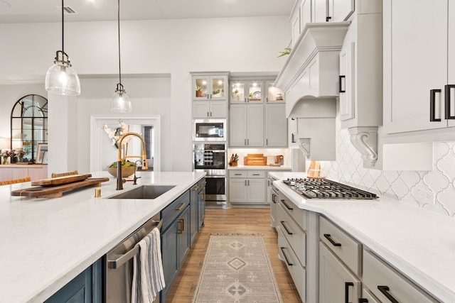 kitchen featuring light wood-style flooring, stainless steel appliances, a sink, visible vents, and light countertops