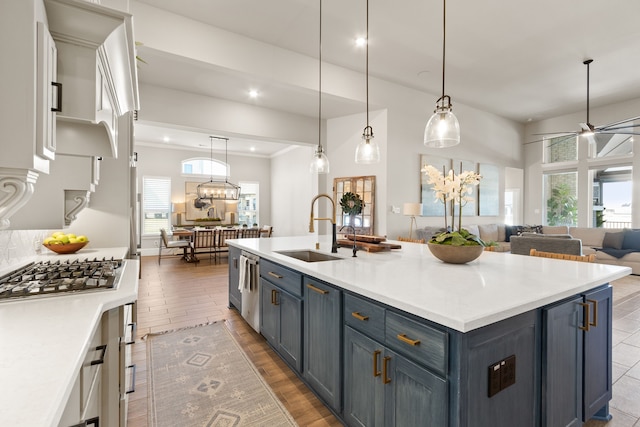 kitchen with open floor plan, stainless steel appliances, light countertops, blue cabinetry, and a sink