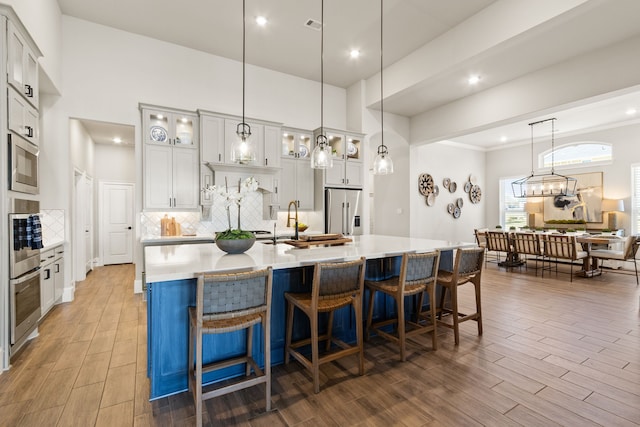 kitchen featuring a large island, wood tiled floor, stainless steel appliances, and light countertops