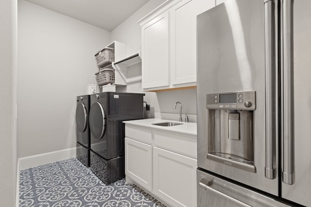 laundry area featuring tile patterned flooring, a sink, baseboards, independent washer and dryer, and cabinet space