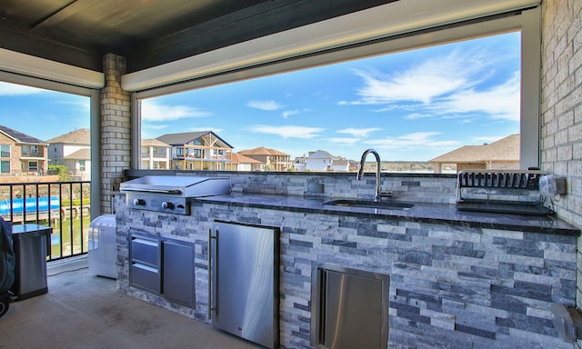 view of patio / terrace with an outdoor kitchen, grilling area, a sink, and a residential view