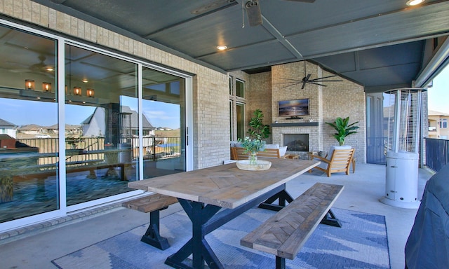 view of patio / terrace featuring outdoor dining space, a large fireplace, and ceiling fan