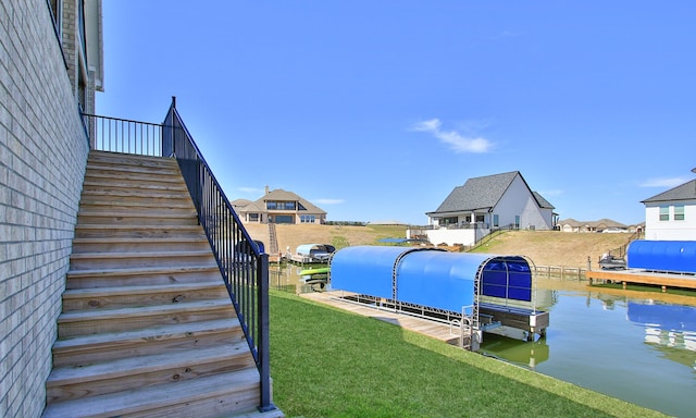 dock area with a water view, stairway, and a lawn