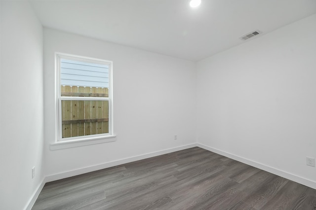 empty room featuring baseboards, visible vents, and dark wood finished floors