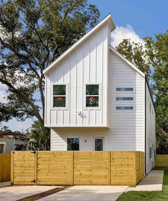 view of side of home with board and batten siding, a gate, and fence