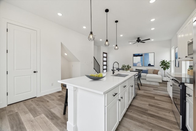 kitchen featuring electric stove, light wood-style floors, open floor plan, white cabinets, and a sink