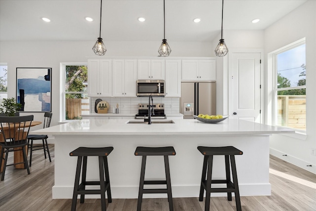 kitchen featuring stainless steel appliances, light countertops, backsplash, white cabinetry, and a sink