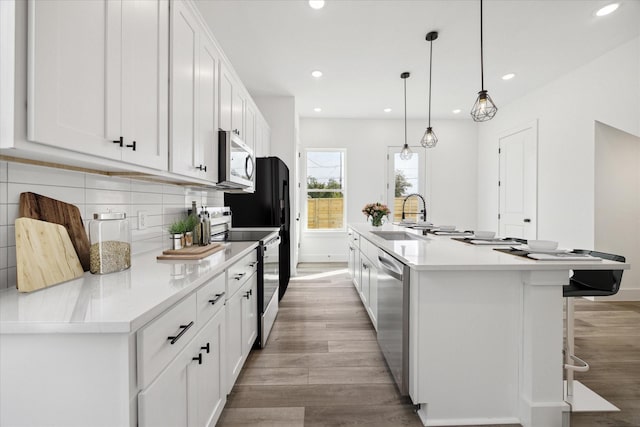 kitchen with appliances with stainless steel finishes, light wood-style floors, a sink, and decorative backsplash