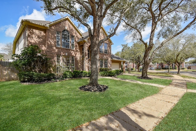 traditional-style home featuring a front lawn, fence, and a garage