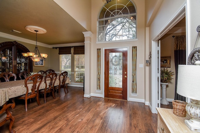 entryway with crown molding, baseboards, dark wood finished floors, an inviting chandelier, and a towering ceiling