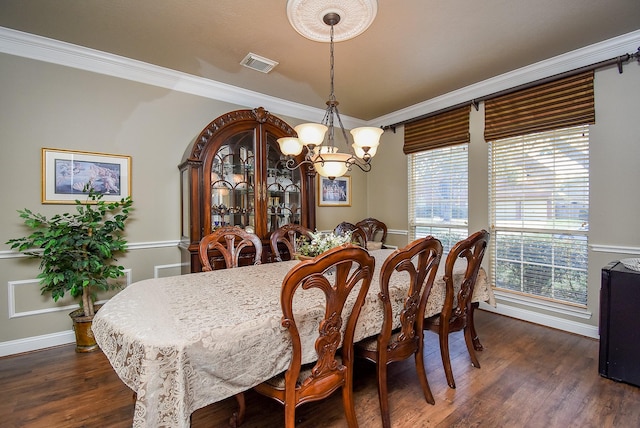 dining space with dark wood finished floors, visible vents, crown molding, and an inviting chandelier