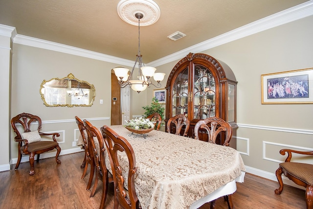 dining room featuring a notable chandelier, dark wood-style floors, visible vents, and ornamental molding