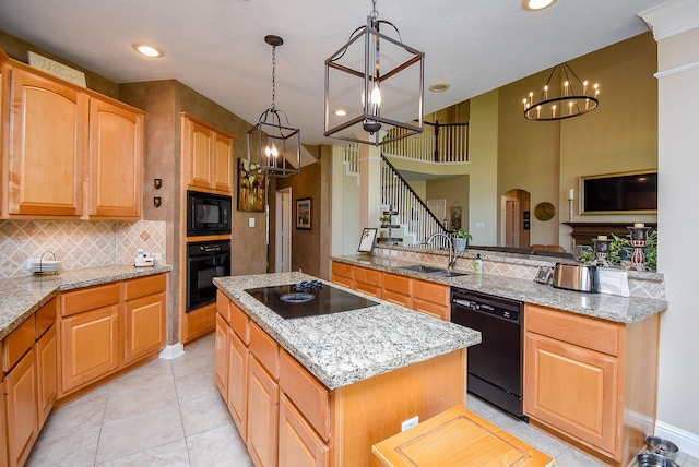 kitchen with a sink, black appliances, a center island, and a chandelier