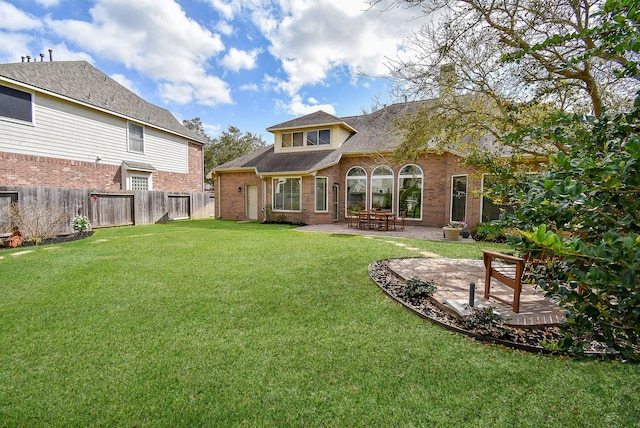 back of property featuring roof with shingles, a yard, a fenced backyard, a patio area, and brick siding