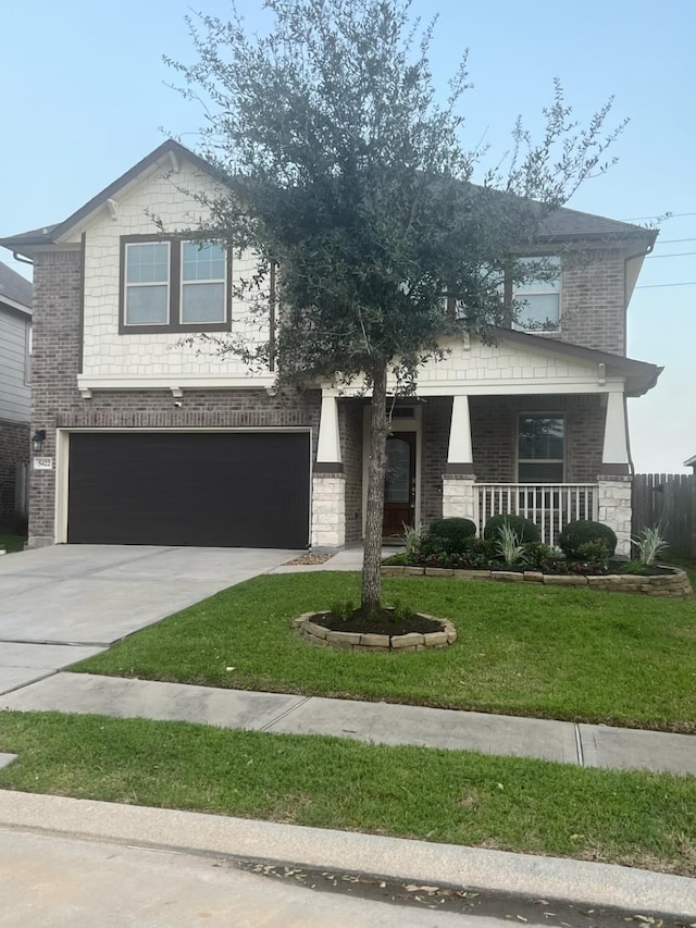 view of front of house with brick siding, a porch, concrete driveway, and a front lawn