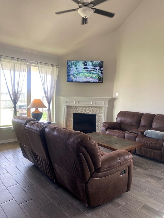 living area with a high end fireplace, wood tiled floor, ceiling fan, and vaulted ceiling