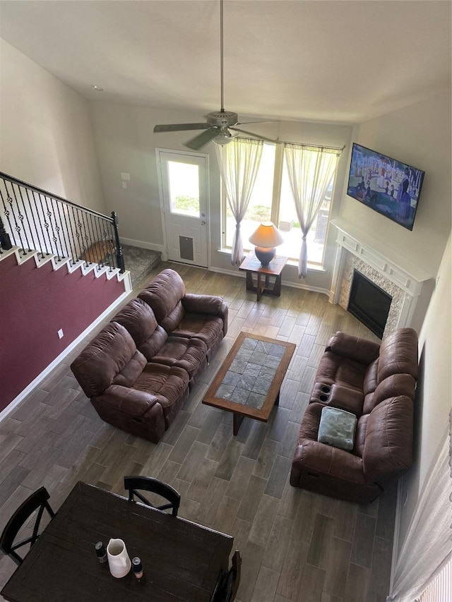 living area with stairway, baseboards, wood finished floors, and a fireplace