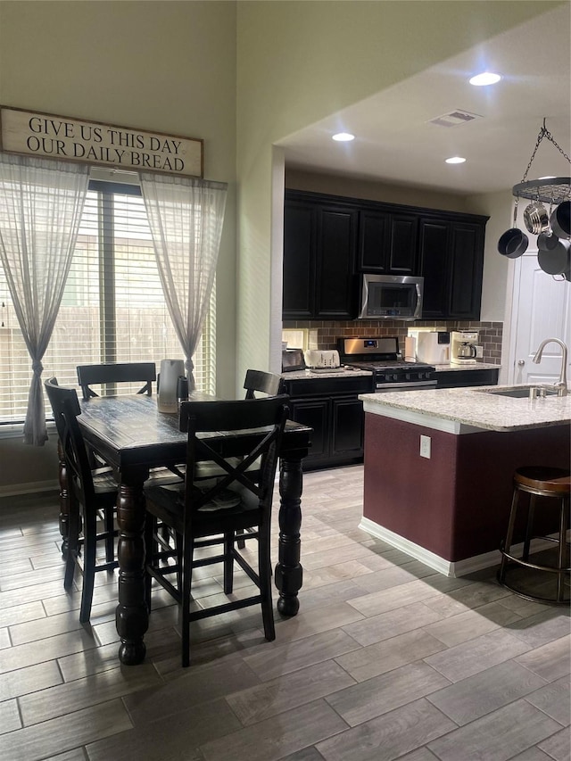 kitchen featuring wood finish floors, visible vents, a sink, appliances with stainless steel finishes, and dark cabinets