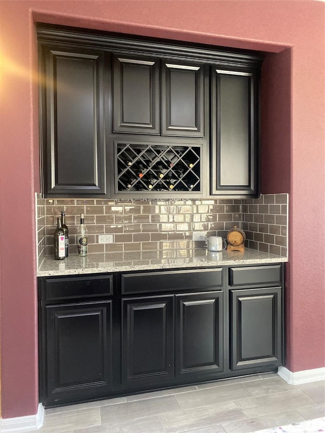 bar with decorative backsplash, a bar, and baseboards